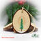 A hand-painted evergreen tree with falling snow on the back of bird wood slice ornaments available for purchase at Cove Creek Photography.